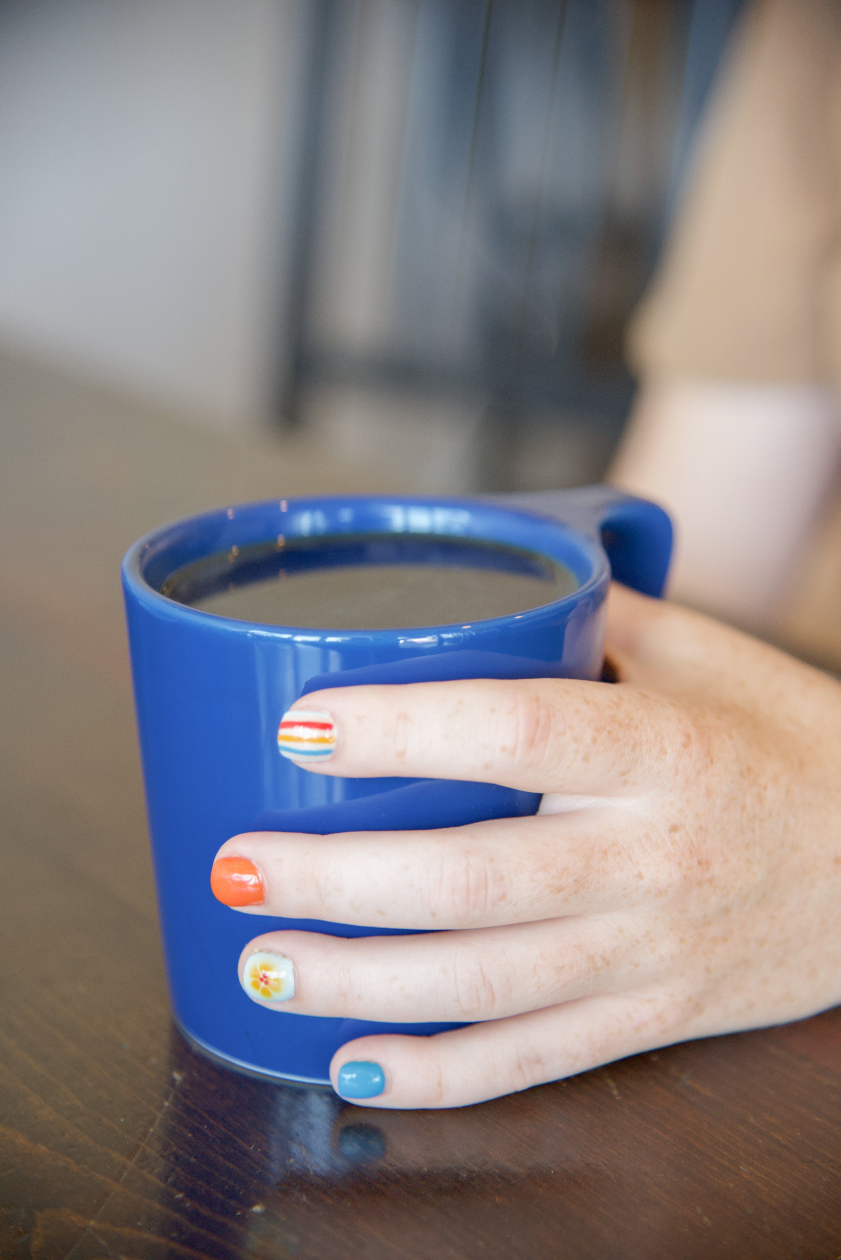 Person holding a brewed coffee in a NotNeutral Lino blue mug.