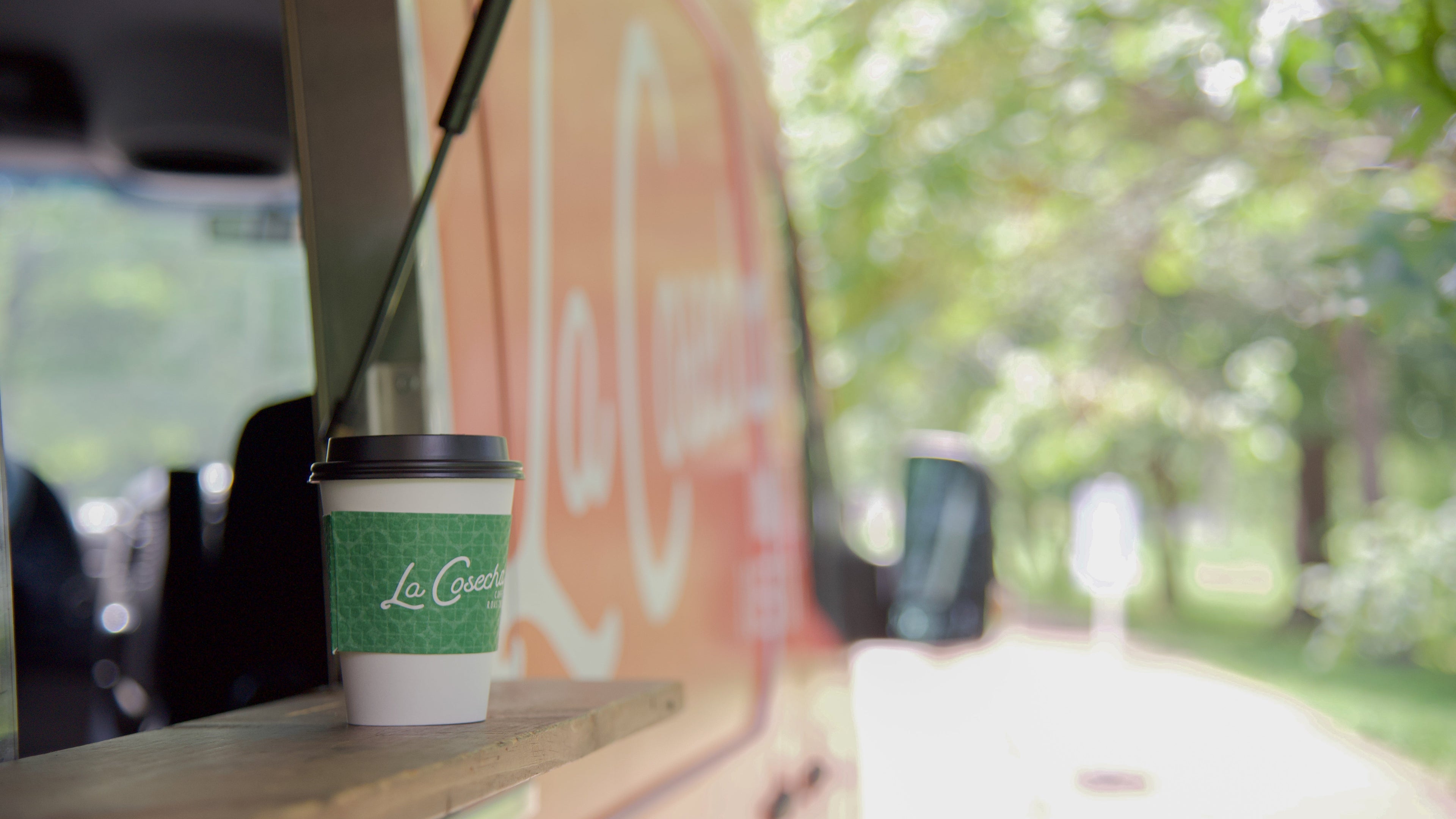 La Cosecha coffee cup on a wooden surface with a blurred outdoor background