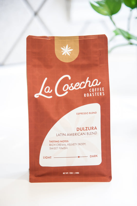 La Cosecha coffee bag on a white background with a plant in the corner