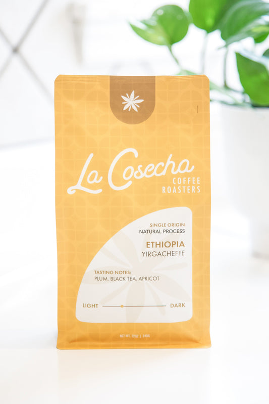 La Cosecha Coffee Roasters package on a white surface with a plant in the background