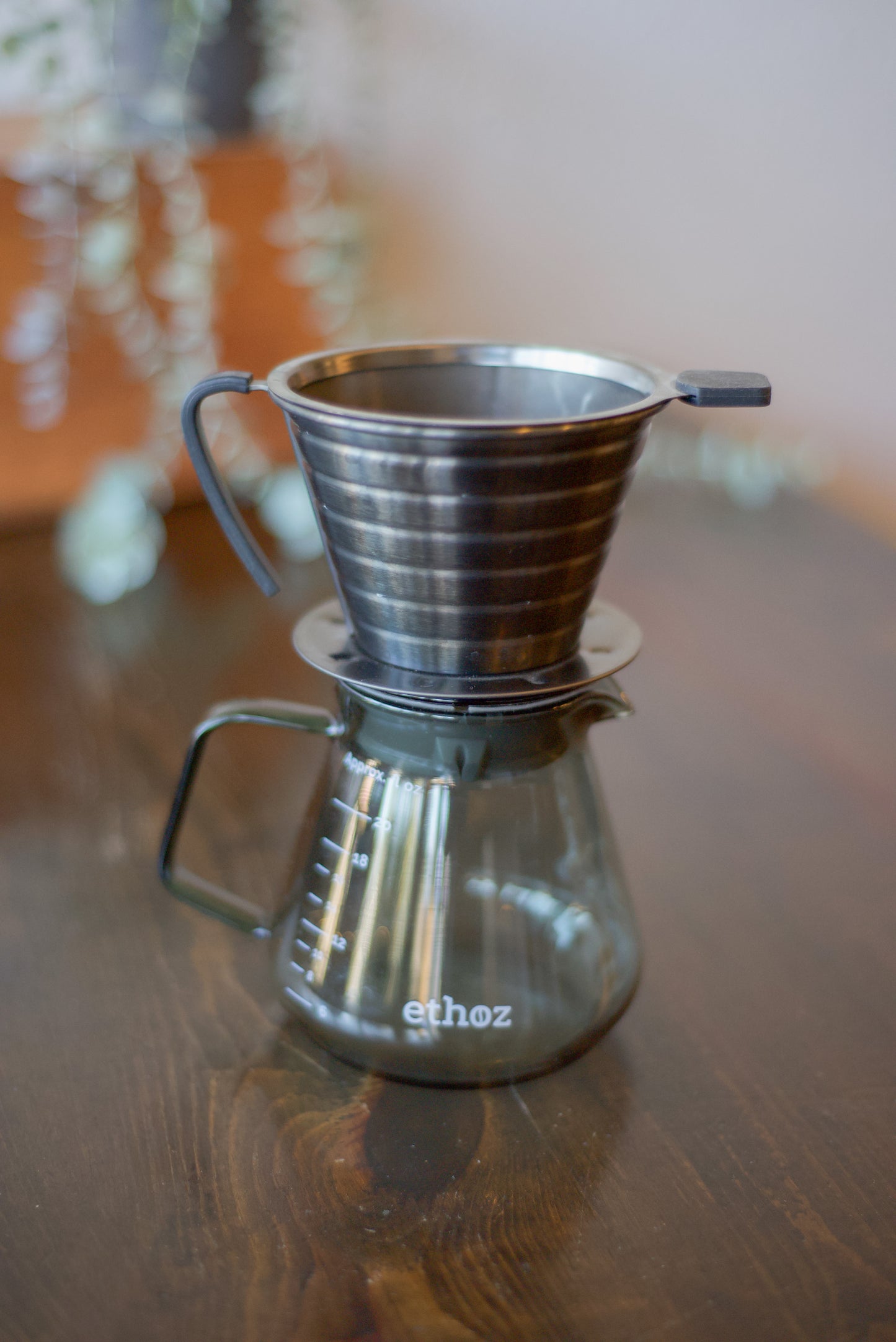 Coffee brewing device with 'ethoz' branding on a wooden surface