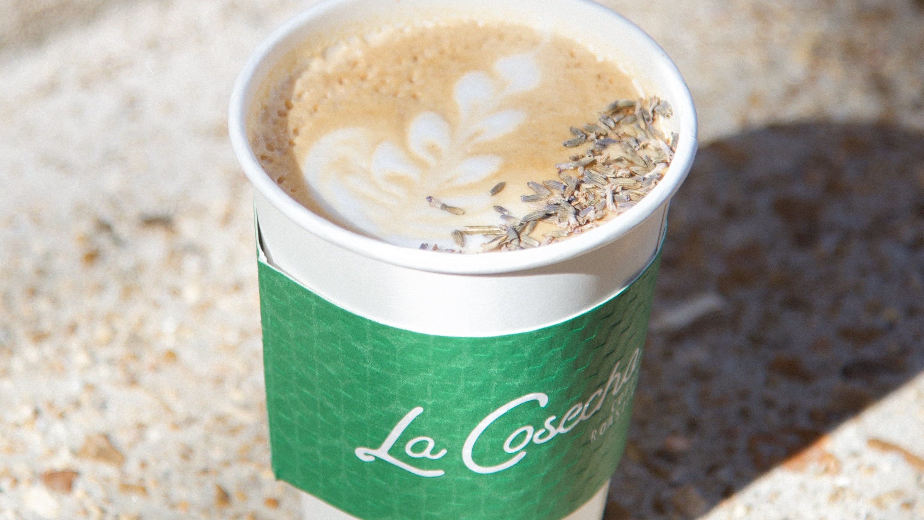 Coffee cup with a green sleeve on a textured surface