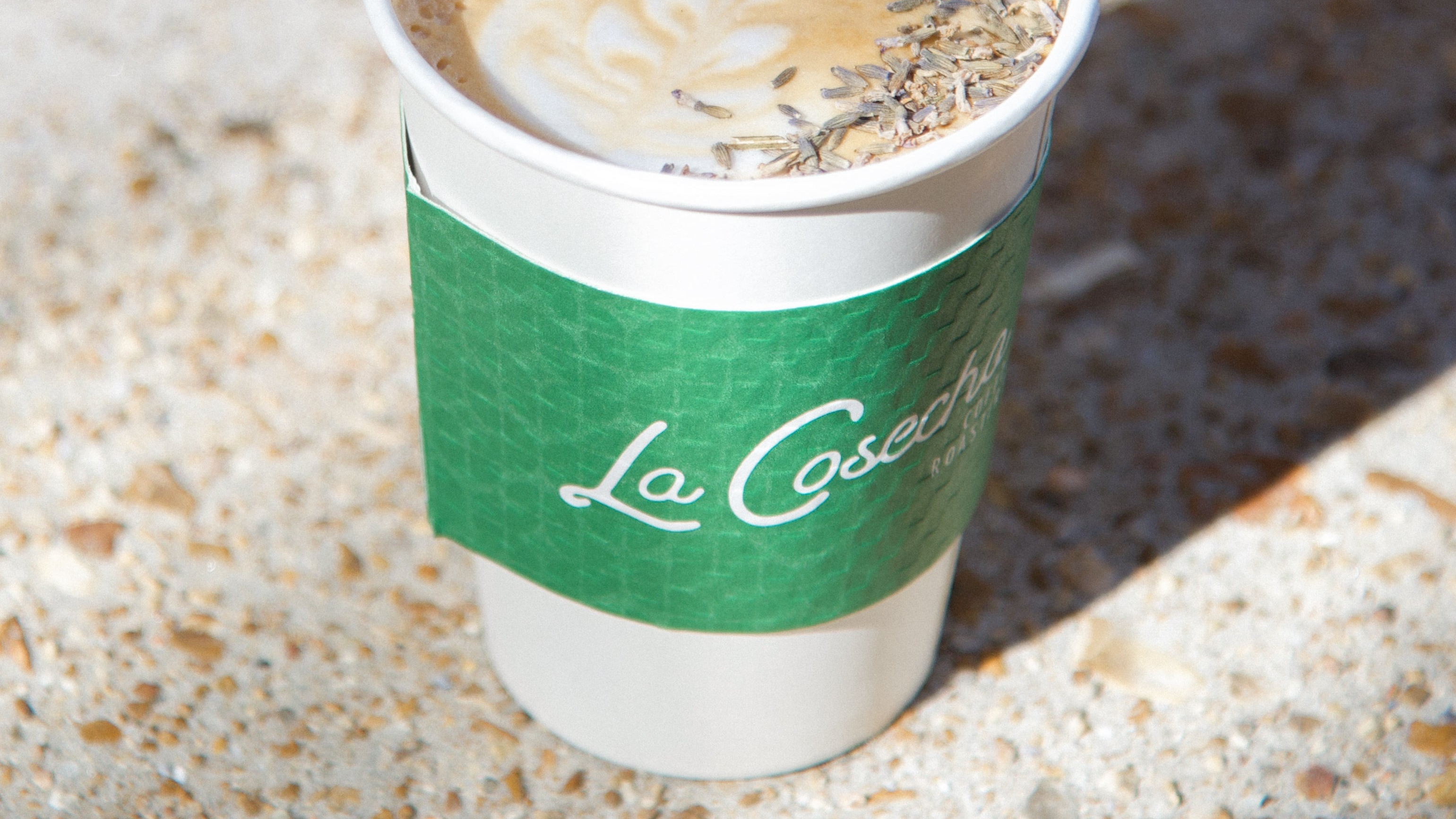 Coffee cup with a green sleeve on a textured surface