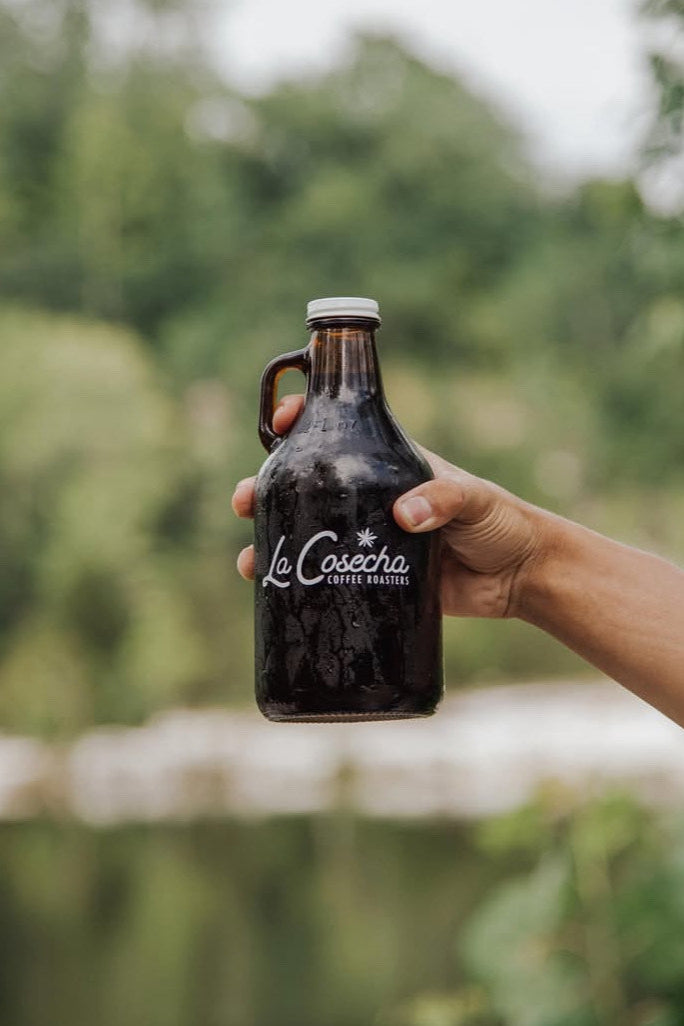 Hand holding a La Cosecha Coffee growler outside