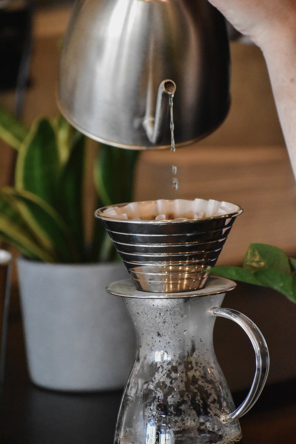 Coffee being poured from a kettle into a coffee filter over a glass carafe.