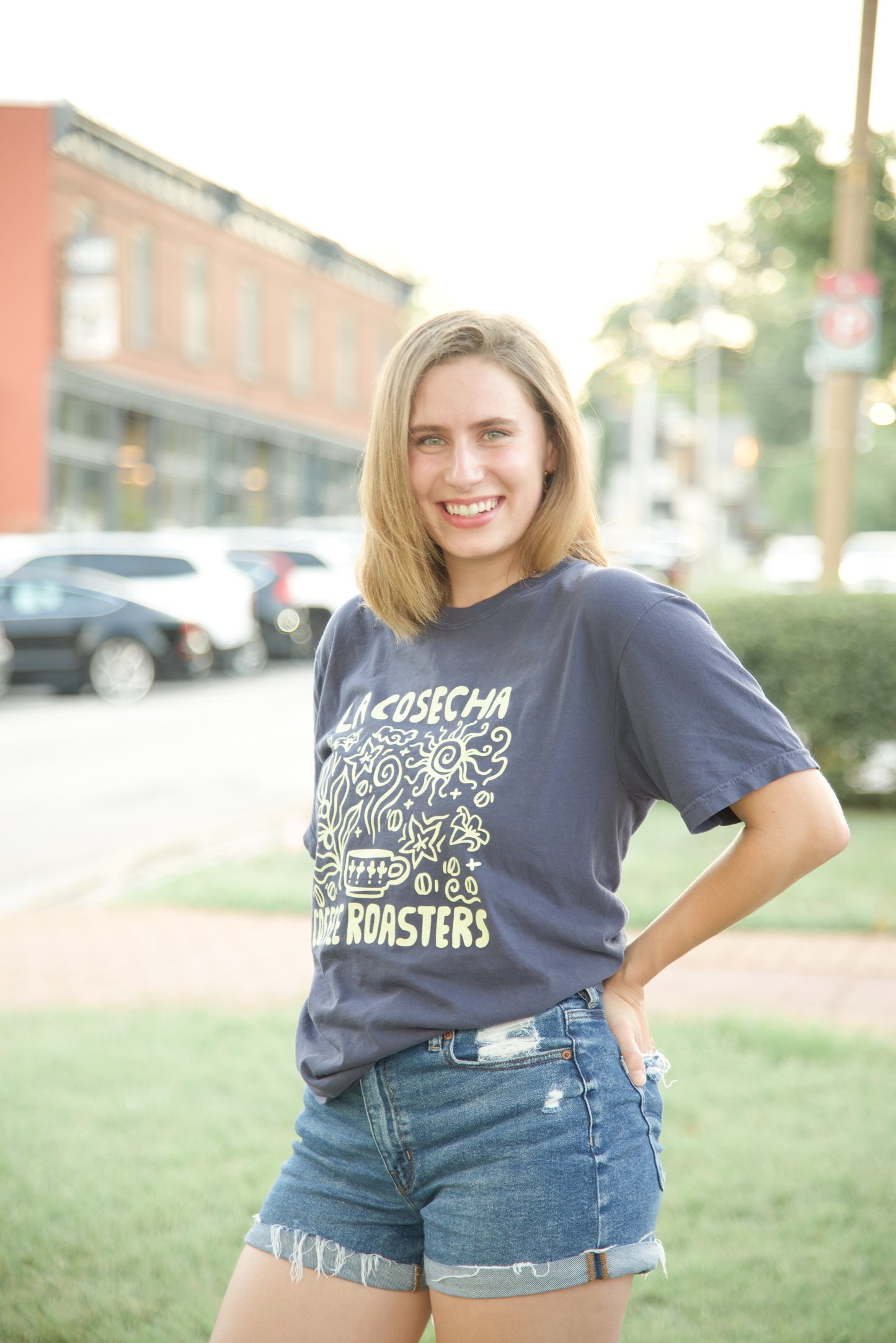 Woman wearing a navy Comfort Colors t-shirt with text and graphics, standing outdoors on a street.