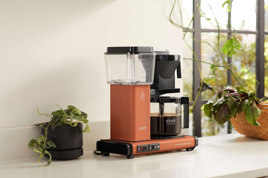 Coffee maker on a kitchen counter with plants in the background