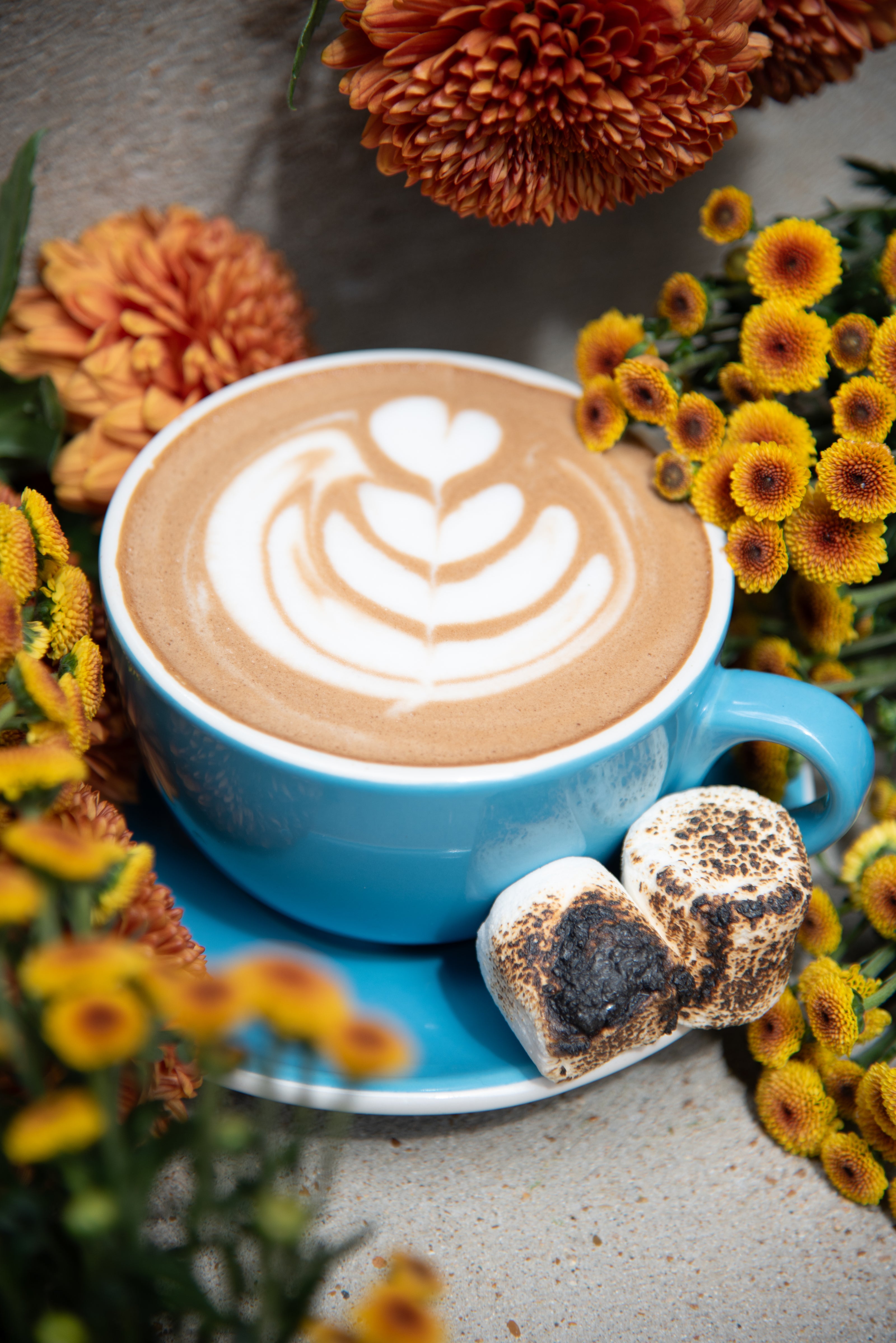 Blue cup of latte with floral decorations on a stone surface