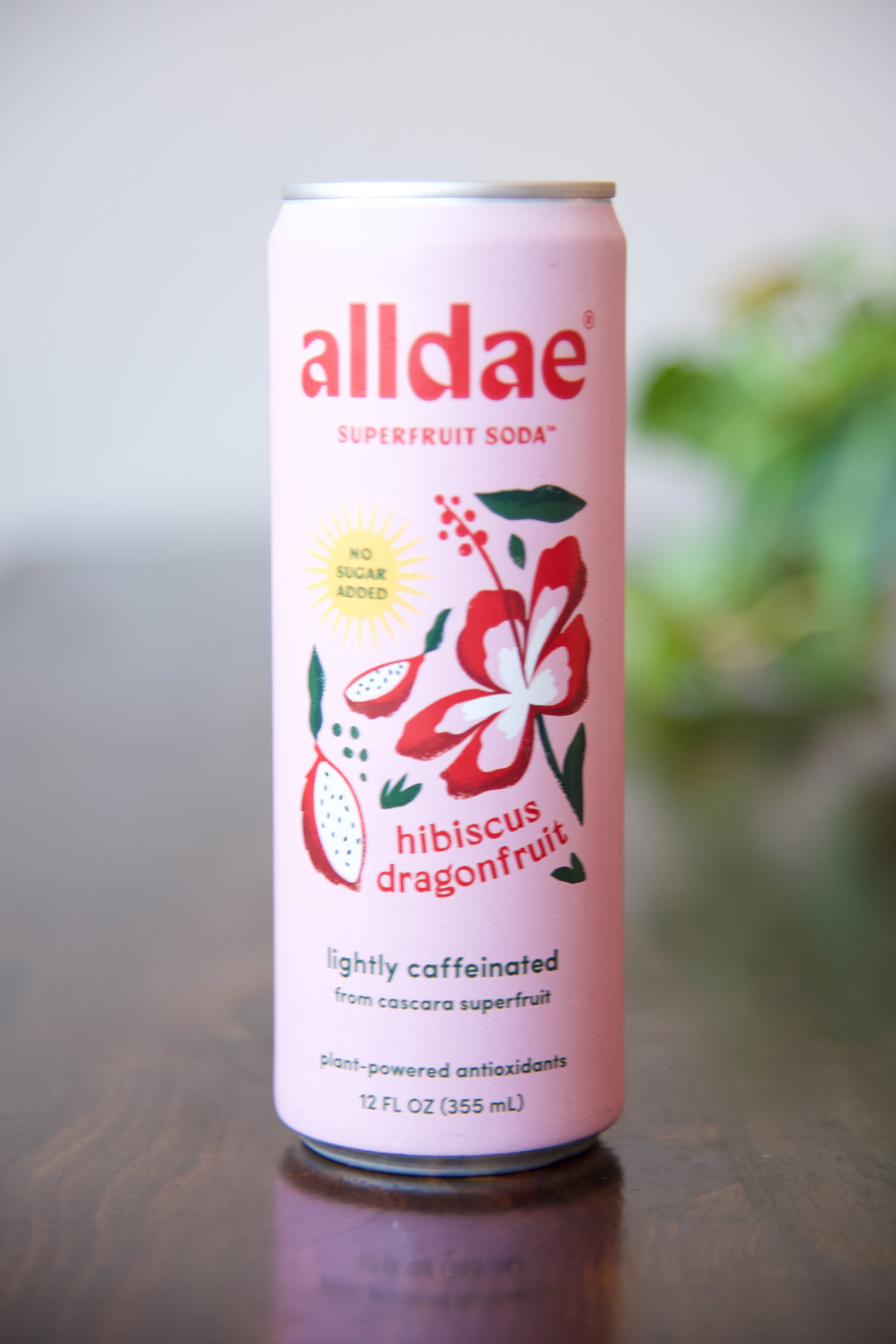 Can of Alldae superfruit soda with hibiscus dragonfruit flavor on a wooden surface.