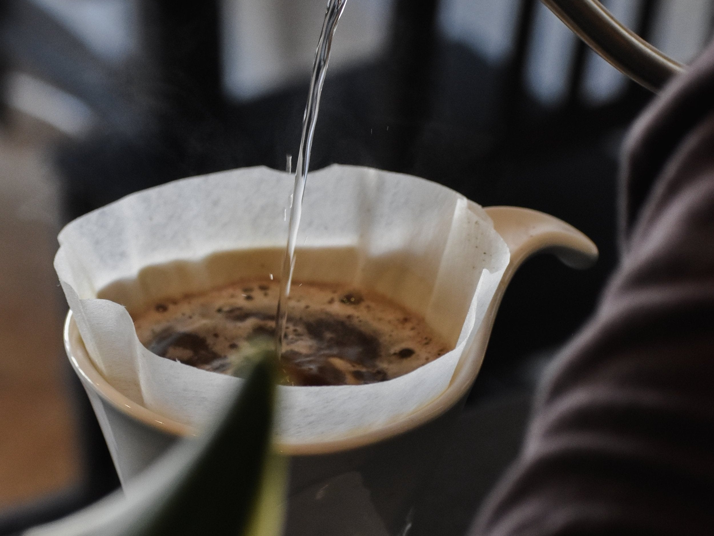Coffee being poured into a filter with a blurred background